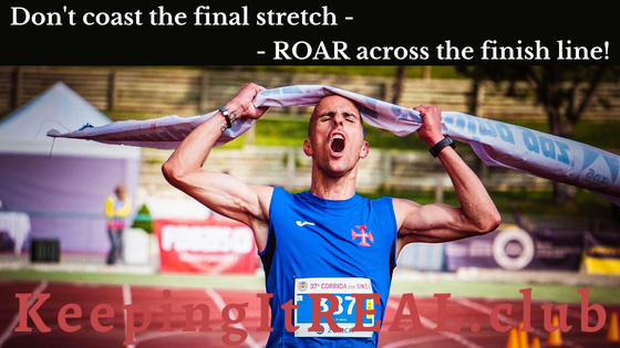 A man running across the finish line, arms raised in victory